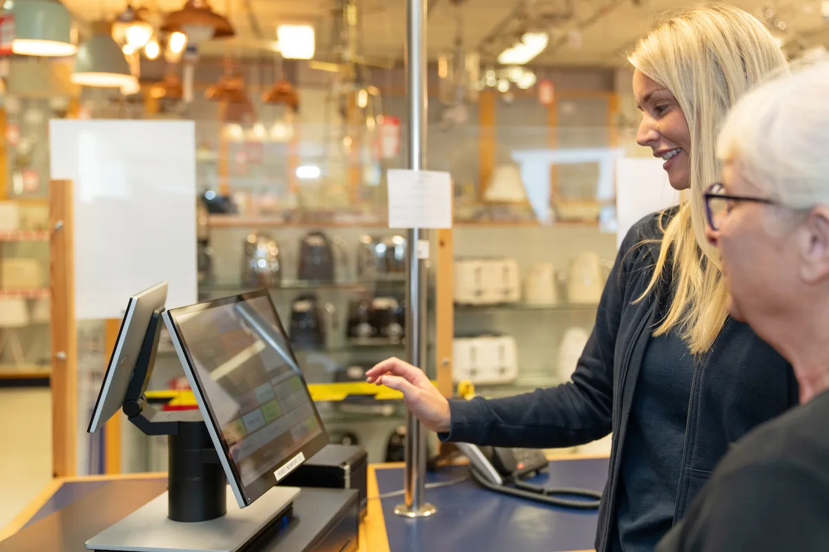 Alex Hurst training Hurts staff member how to use the tills